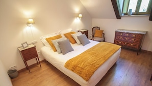 A bedroom with a bed, bedside lamps, a nightstand, a chair, and a dresser.