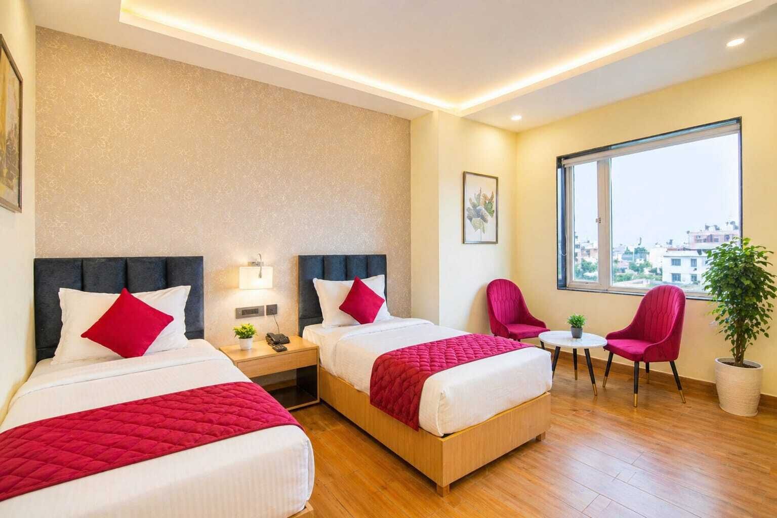 A hotel room with two beds, a small table, a chair, and a large window.