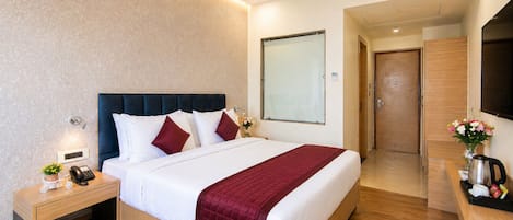 A modern hotel room with a large bed, bedside table, and a TV.
