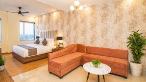 A modern bedroom with a bed, a sofa, a round coffee table, and a ceiling fan. - Hotel Avadh Classio (Faizabad)