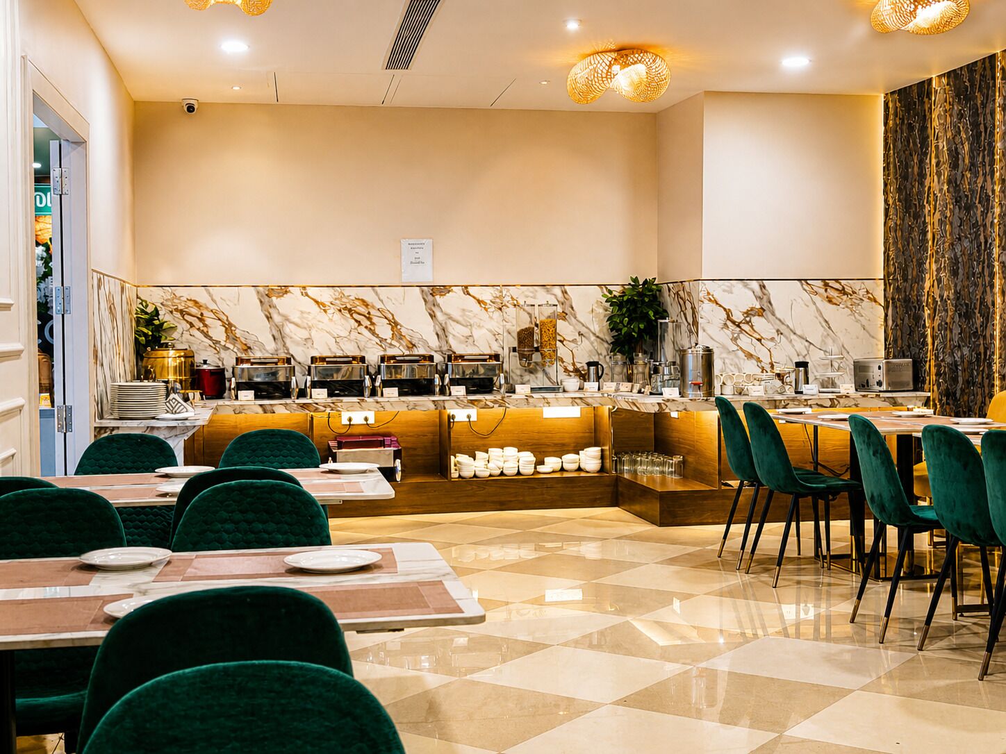 Un restaurante con pared de mármol, mostrador de buffet y sillas tapizadas en verde.
