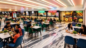 A spacious food court with multiple dining areas, various food outlets, and a modern ceiling design. - Hotel Avadh Classio (Faizabad)