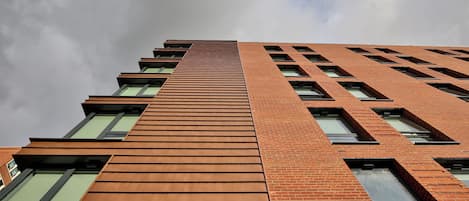 Un edificio alto de ladrillo con múltiples ventanas y diseño moderno.