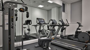 Een sportschool met diverse trainingsapparaten, waaronder een loopband, elliptische trainer en gewichtstoestellen.