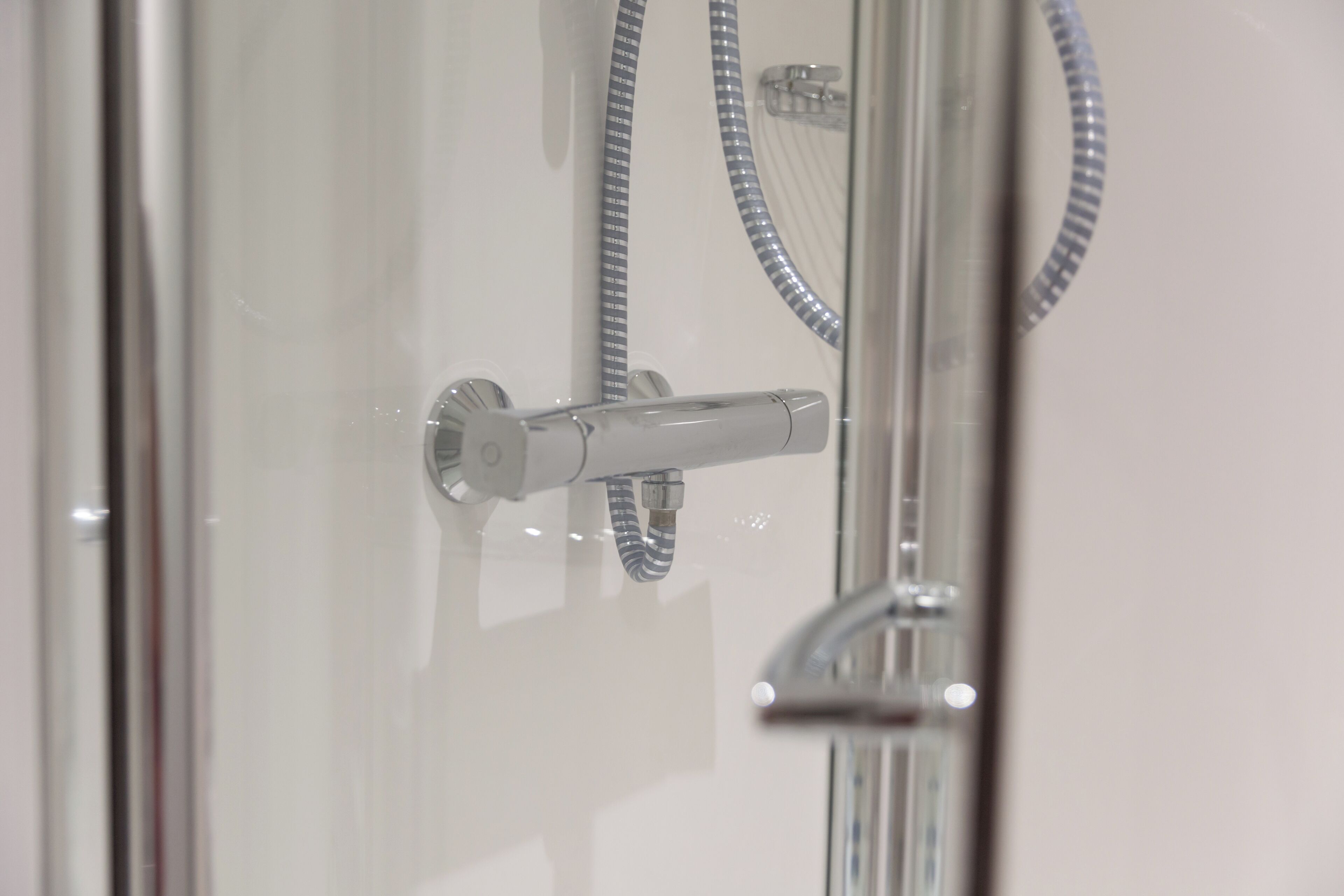 A modern shower with a handheld showerhead and a flexible hose.