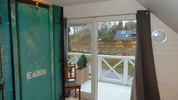 A room with a sliding glass door leading to an outdoor area, a wooden chair, and a small potted plant.