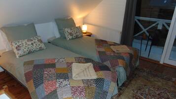 Un dormitorio con dos camas, una colcha estampada y una mesita de noche con una lámpara.