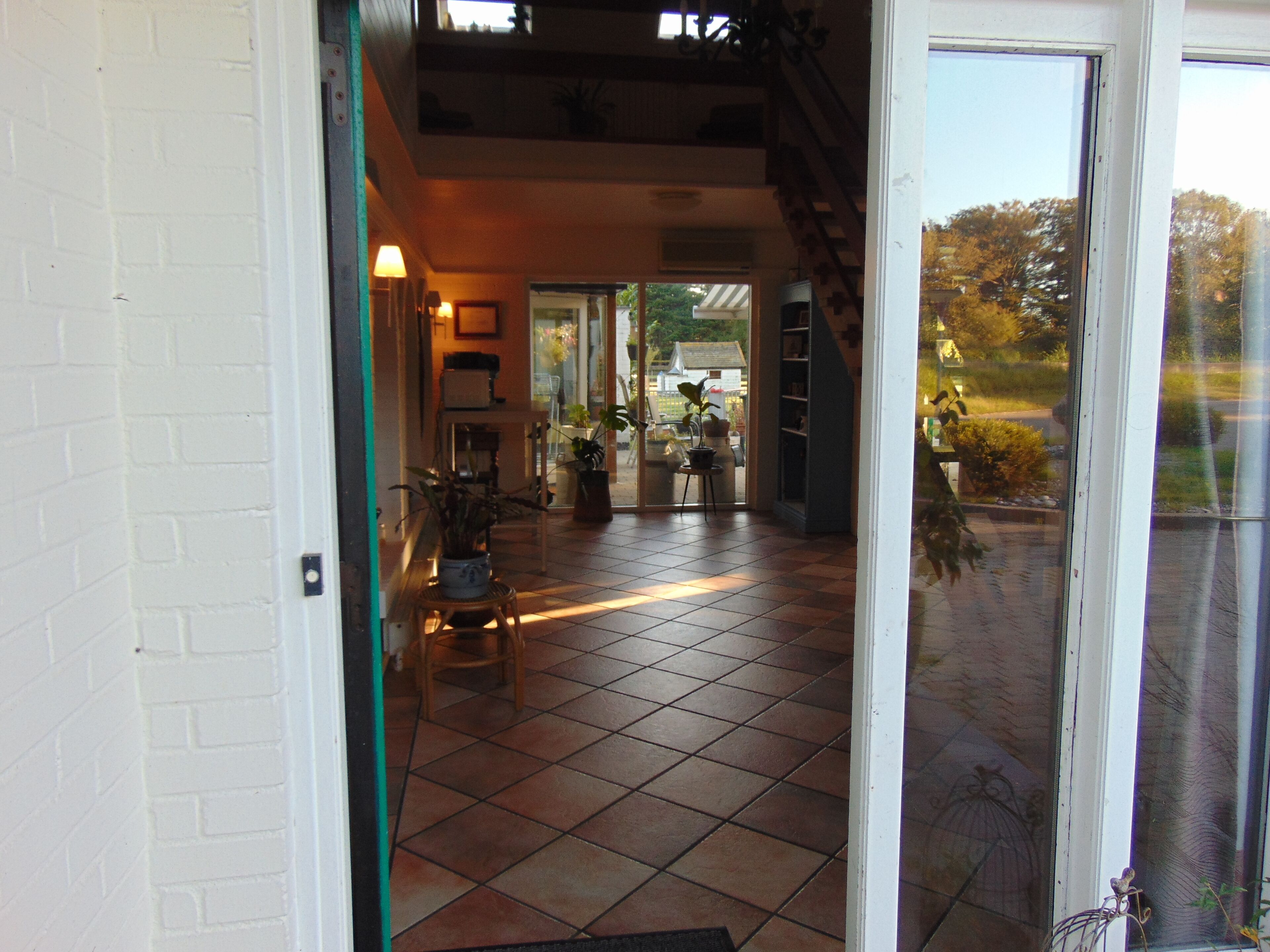 Un hall d’entrée spacieux, doté d’un sol carrelé, qui mène à une porte en verre.