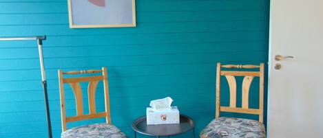 Two wooden chairs with patterned cushions, a small round table with a tissue box, and a door with a handle.