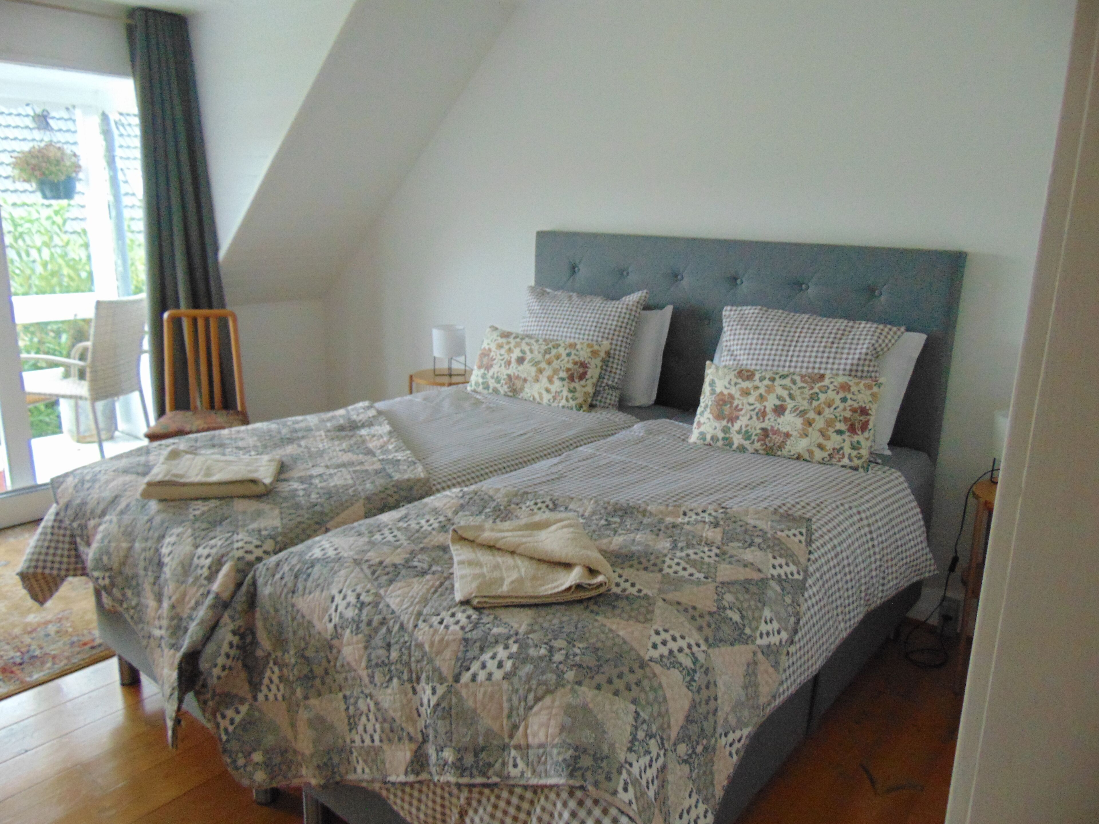A bedroom with a large bed, two bedside tables, and a window with curtains.