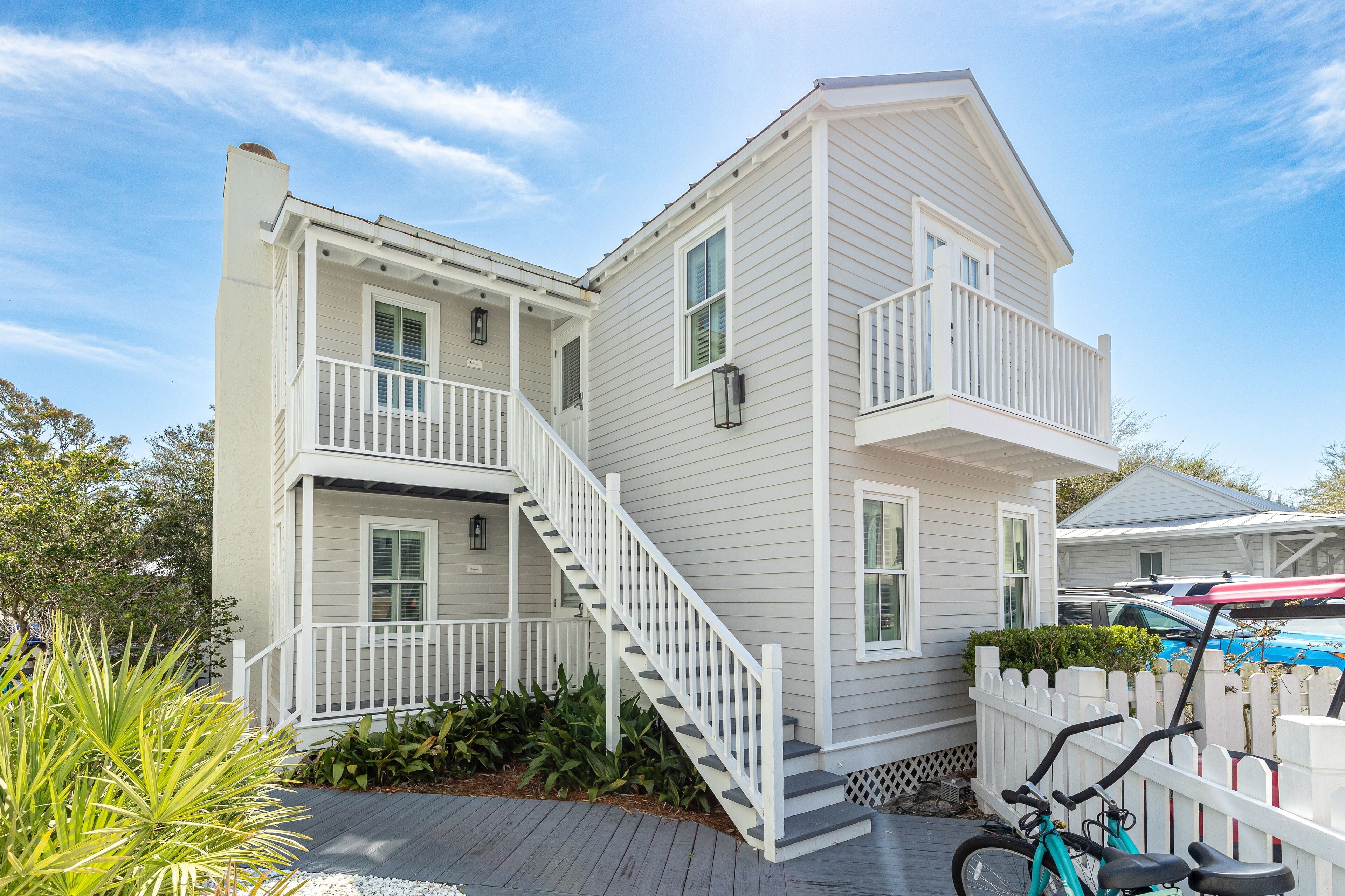 A two-story house with a front porch, a staircase, and a white picket fence.