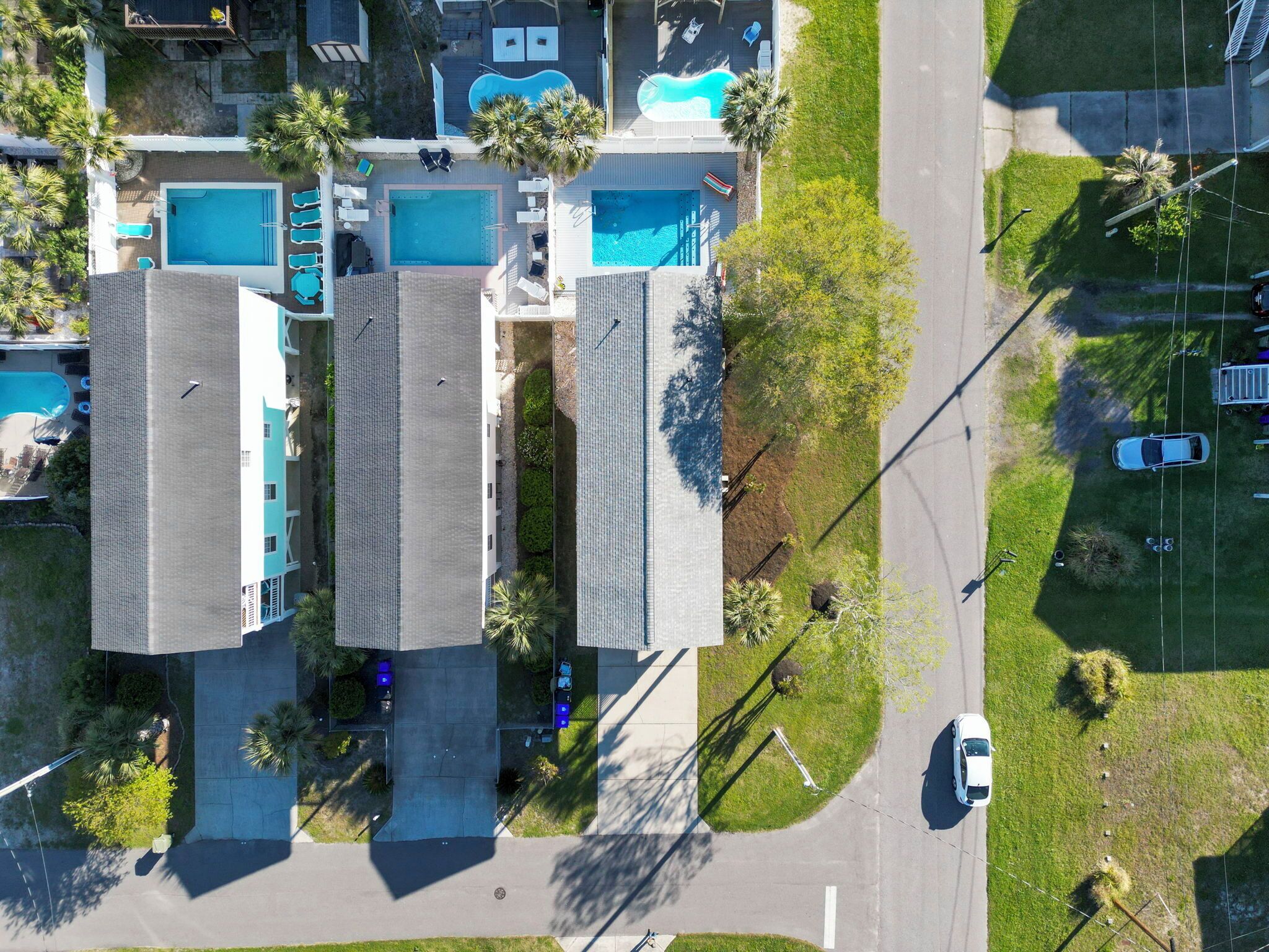Vista aérea de un hotel con varias piscinas, un estacionamiento y zonas verdes circundantes.