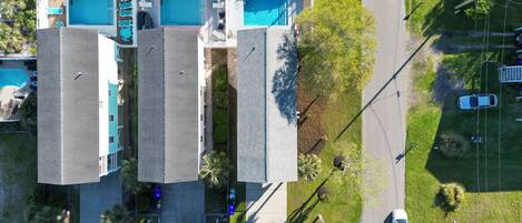 Vista aérea de un hotel con varias piscinas, un estacionamiento y zonas verdes circundantes.