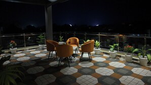 Eine Dachterrasse mit orangefarbenen Stühlen, Topfpflanzen und einem gefliesten Boden.