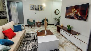 A living room with a sofa, coffee table, and artwork. - The Nest Kampala (Kampala)