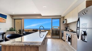 Una cucina moderna con isola centrale, elettrodomestici in acciaio inossidabile e vista sull'esterno.