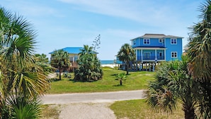 A two-story blue house with a balcony, surrounded by palm trees and a clear sky. - ☀️Short, 3 Min Walk to Beach | Gulf Views | Papa's Palmetto Place☀️ (Indian Pass)