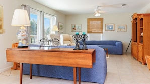 A living room with a wooden coffee table, a blue sofa, and a wooden cabinet. - ☀️Short, 3 Min Walk to Beach | Gulf Views | Papa's Palmetto Place☀️ (Indian Pass)