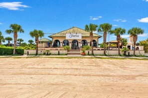 A hotel with a sign reading 'Marina' and a sandy ground in front.