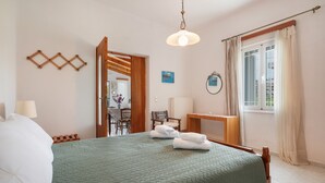 Habitación de hotel con cama, escritorio, silla, lámpara y ventana con cortinas.