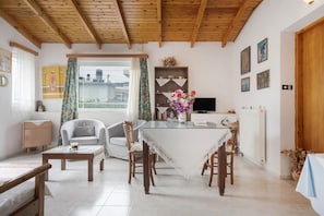 A dining area with a table, chairs, a television, and a view of the outside.