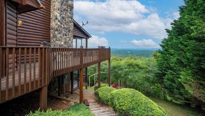 A wooden cabin with a stone exterior, a balcony, and a view of the forest. - Forever View- Mountain View Cabin (Blue Ridge)