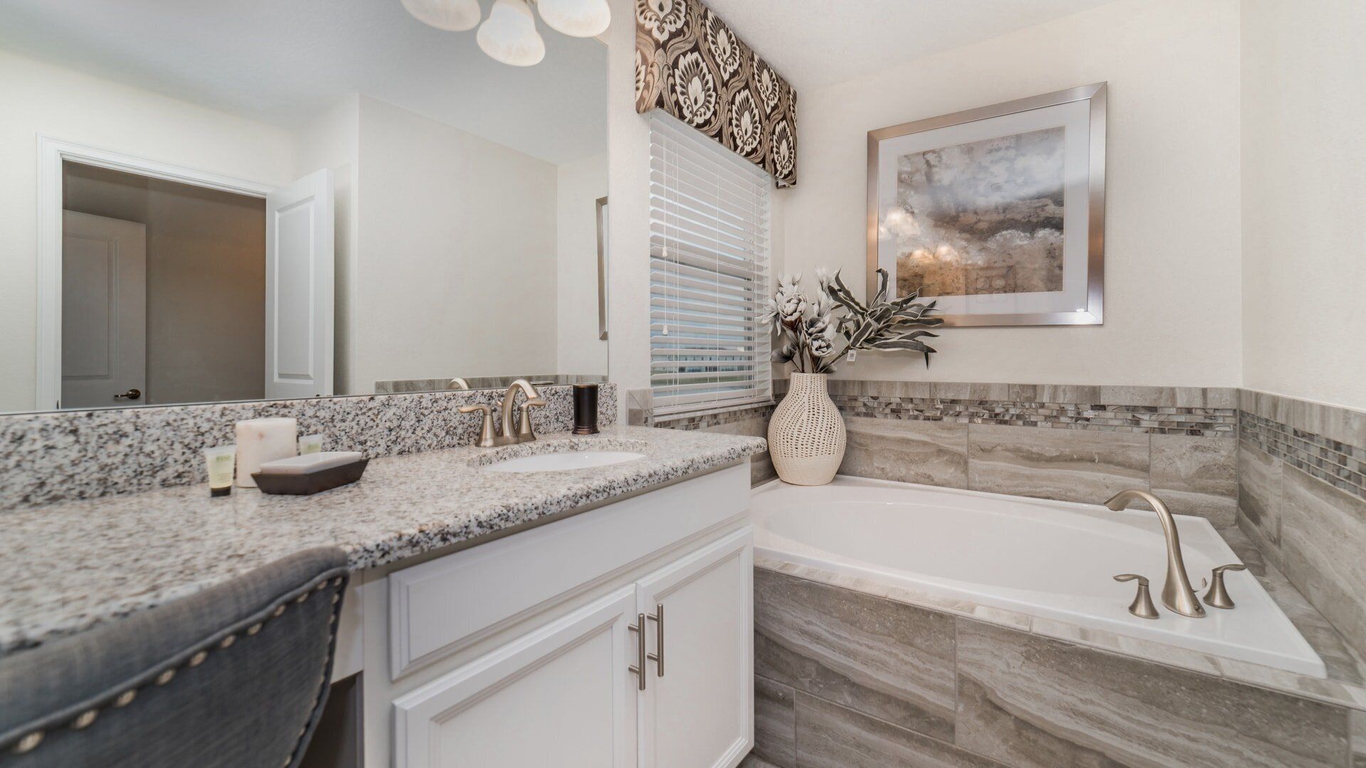 A modern bathroom with a granite countertop, a freestanding bathtub, and a large mirror.