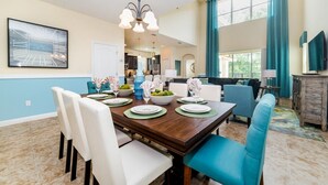 A dining area with a wooden table set for four, chairs, and a bowl of fruit. - BUC2979 (Kissimmee)
