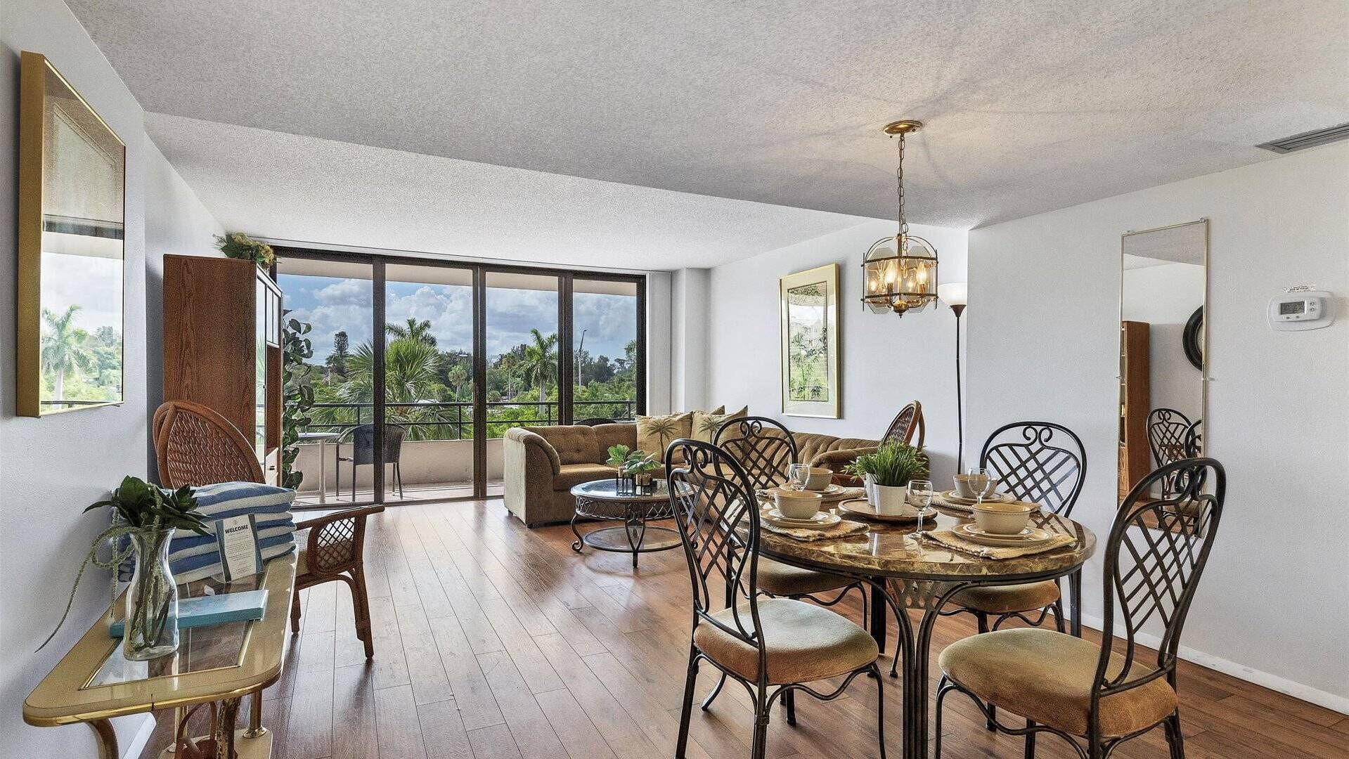 A spacious dining area with a round table, multiple chairs, and a view of greenery outside.