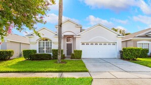 A residential house with a white exterior, a garage, and a well-maintained lawn. - Windsor Palms Resort Vacation Home WP2209 (Kissimmee)