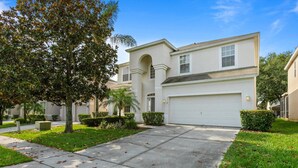A two-story house with a white exterior, a garage, and a well-maintained lawn. - Windsor Hills Resort Vacation Home  TS7718 (Kissimmee)