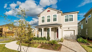 A two-story residential building with a front porch, a garage, and a well-maintained garden. - Solara Resort Vacation Home 5BR (Kissimmee)
