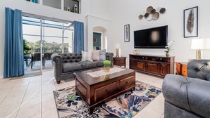 A spacious living room with a grey sofa, a coffee table, and a flat-screen TV. - Windsor Palms Resort Vacation Home 5BR (Kissimmee)