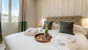 A hotel room with a large bed, a bedside table with a bottle and glasses, and a tray with food and drinks. - 69 Suite Boutique (Rome)