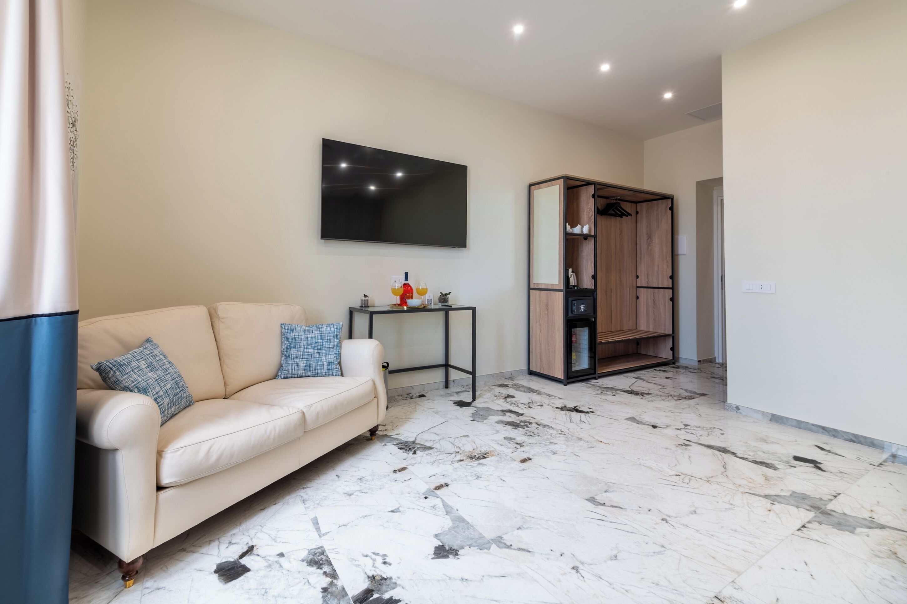 A living room with a sofa, a flat-screen TV, a small table, and a wooden wardrobe. - 69 Suite Boutique (Rome)