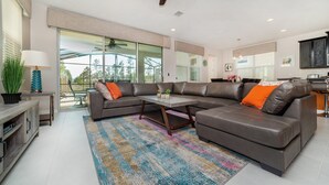 A modern living room with a sectional sofa, a coffee table, and a large window. - Npt1508 (Kissimmee)