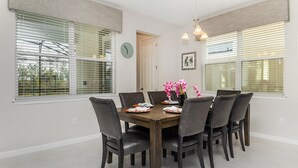 A dining room with a wooden table, six chairs, and a vase of pink flowers. - Npt1508 (Kissimmee)