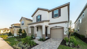 A modern residential building with a beige facade, multiple garage doors, and a well-maintained front yard with landscaping. - Npt1508 (Kissimmee)