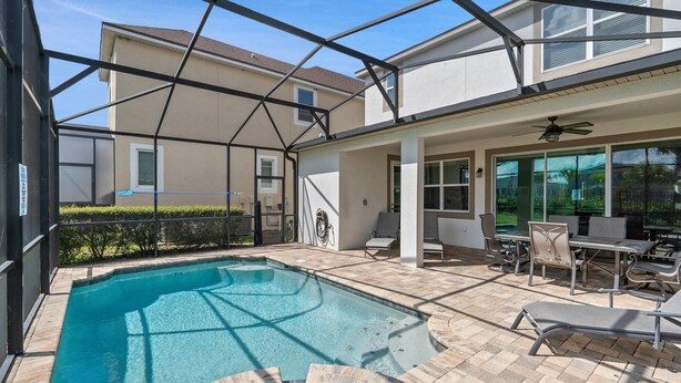 A swimming pool with a covered patio area, outdoor seating, and a view of the house. - Npt1508 (Kissimmee)