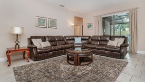 A living room with a brown leather sectional sofa, a wooden coffee table, a patterned rug, and two framed artworks on the wall. - Okb5160 (Davenport)