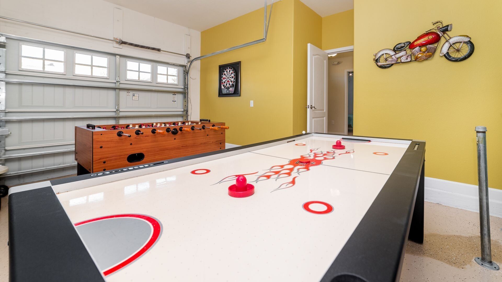 Une pièce avec une table de baby-foot, un jeu de fléchettes et une décoration murale sur le thème de la moto.
