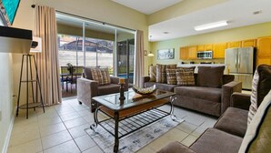 A living room with a sofa, armchairs, a coffee table, and a dining table. There is a kitchen area with cabinets and appliances. - Mnl2678 (Kissimmee)