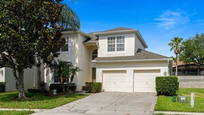A two-story house with a garage, a front yard, and a clear blue sky. - Mnl2678 (Kissimmee)