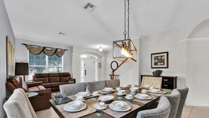 Comedor con una mesa larga dispuesta para seis personas, rodeado de sillas tapizadas en gris.