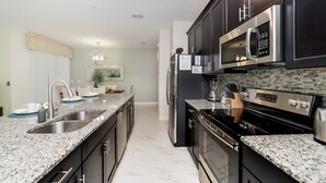 A modern kitchen with granite countertops, stainless steel appliances, and dark cabinetry. - DOG9041 (Davenport)