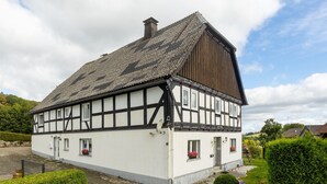 A traditional half-timbered house with a steep gabled roof, a chimney, and a small porch area.