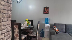 A living room with a dining table, chairs, a water dispenser, and a sofa. - The colored house 3 bedroom apartment (Athiriver)