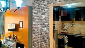 A compact living space with a kitchenette, a dining area, and a TV. - The colored house 3 bedroom apartment (Athiriver)