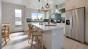 Una cocina moderna con una isla central, electrodomésticos de acero inoxidable e iluminación colgante.