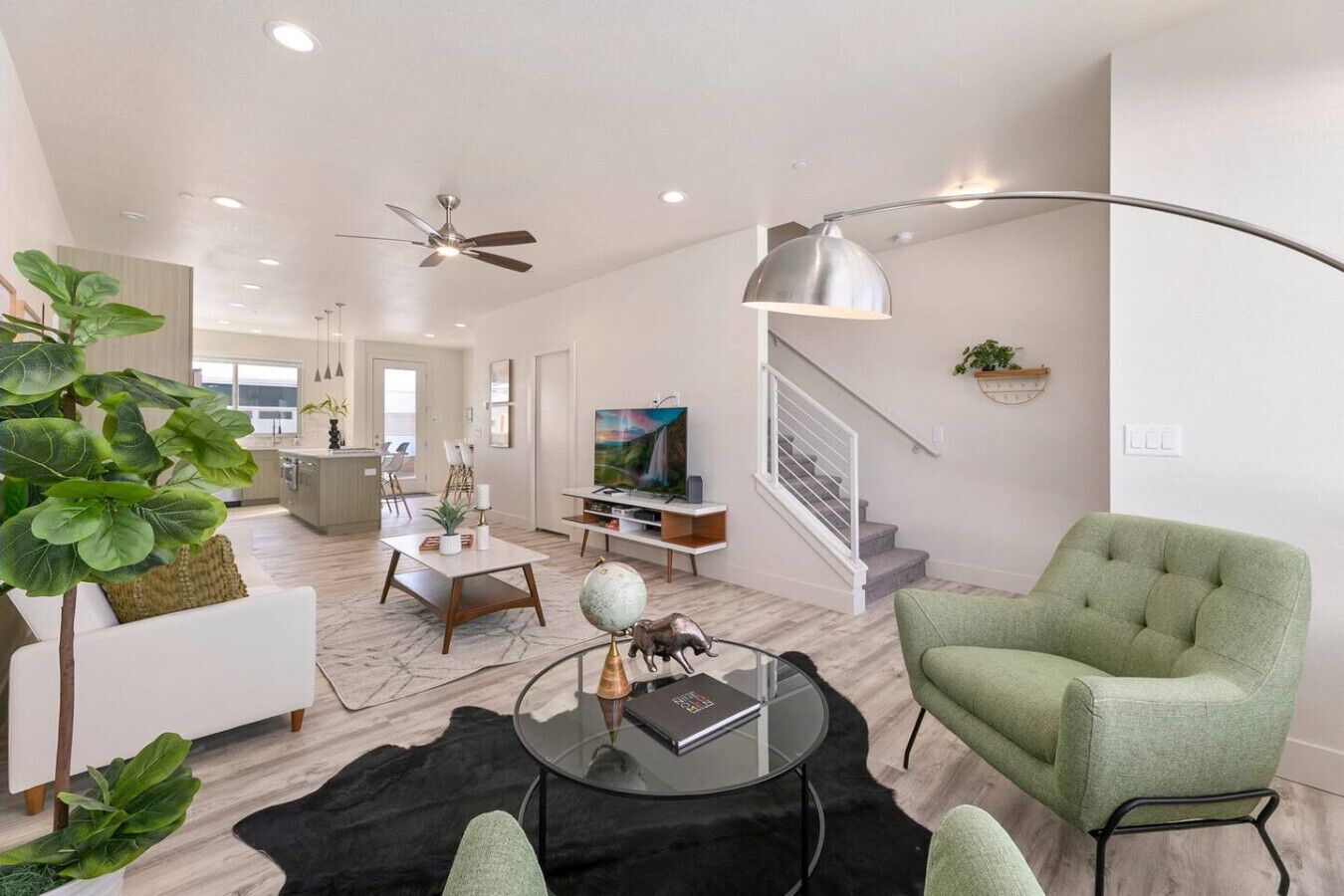 A modern living room with a green armchair, a glass coffee table, and a flat-screen TV.